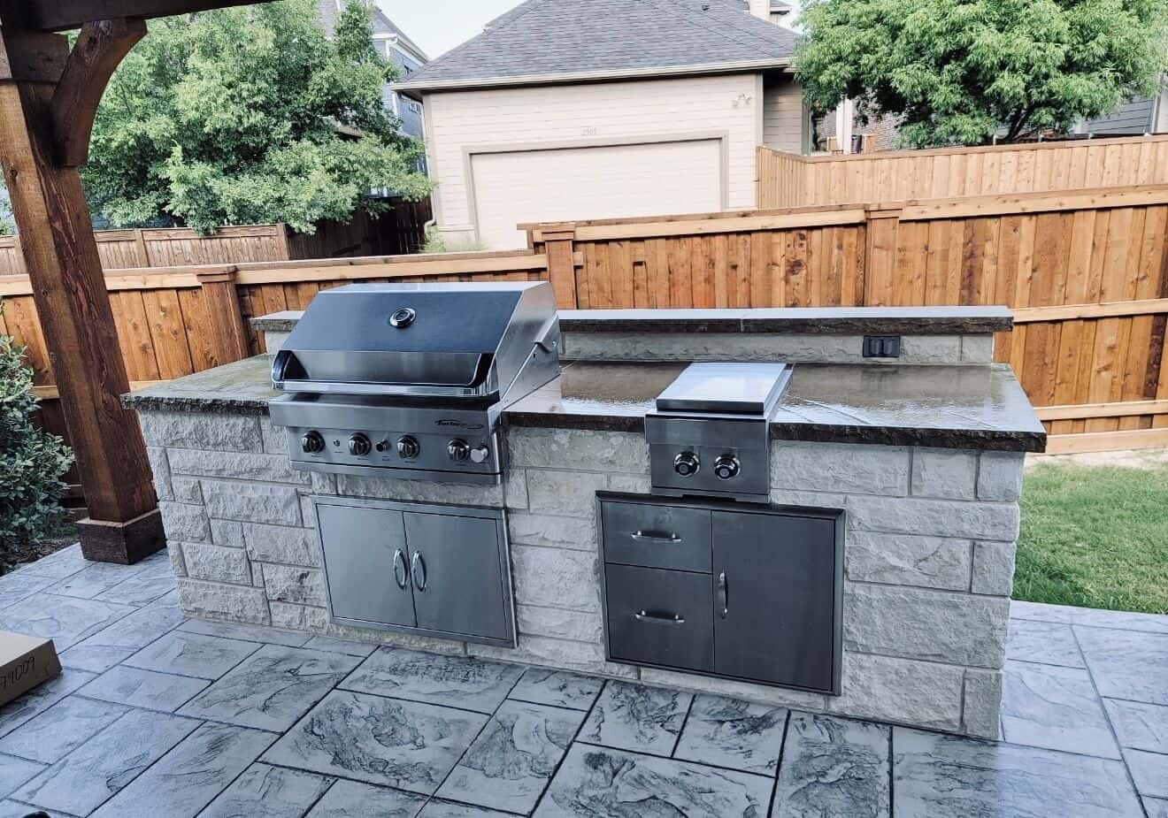 Slate-stamped concrete patio around a limestone outdoor kitchen by Professional Brick & Stone Works